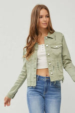 Trendy cropped denim jacket with raw hem, styled with a white top and blue jeans, perfect for a casual chic look.