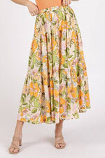 Woman wearing a floral print elastic waist tiered skirt with vibrant orange and green flowers, perfect for a bohemian outfit.