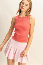 Stylish woman wearing a pink ribbed round neck sweater tank paired with a flouncy pink skirt.