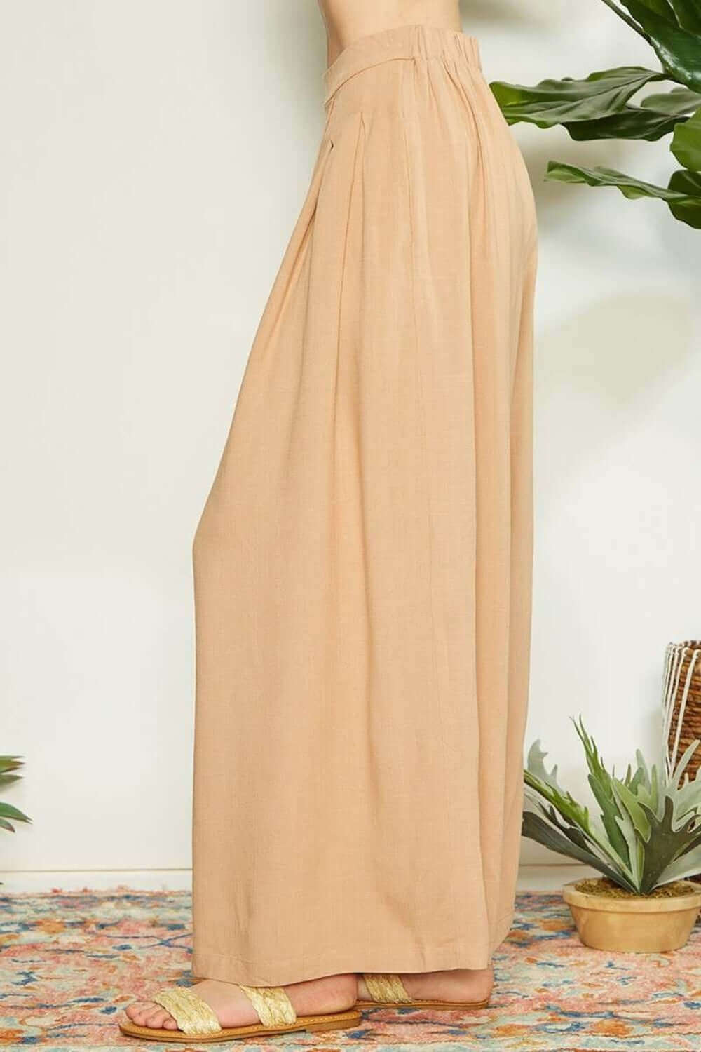 Side view of wrap pleating detail wide leg pants in beige, showcasing modern elegance and chic wide leg silhouette.