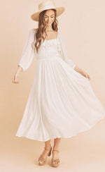 Model wearing Aemi + Co ruffled smocked square neck balloon sleeve dress, styled with a straw hat and platform sandals.