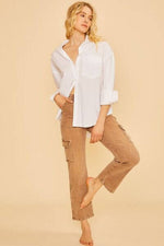 Model showcasing Annie Wear straight leg jeans with cargo pockets paired with a stylish white shirt against a beige background.