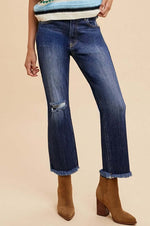 Model wearing distressed raw hem straight leg cropped jeans paired with stylish ankle boots.