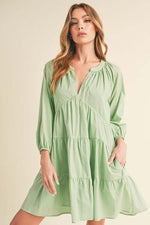 Aemi + Co Notched Balloon Sleeve Tiered Mini Dress in soft green, featuring flirty tiered layers and stylish balloon sleeves.