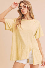 Stylish woman wearing a yellow asymmetrical front slit t-shirt with round neck and raglan sleeves, paired with shorts.