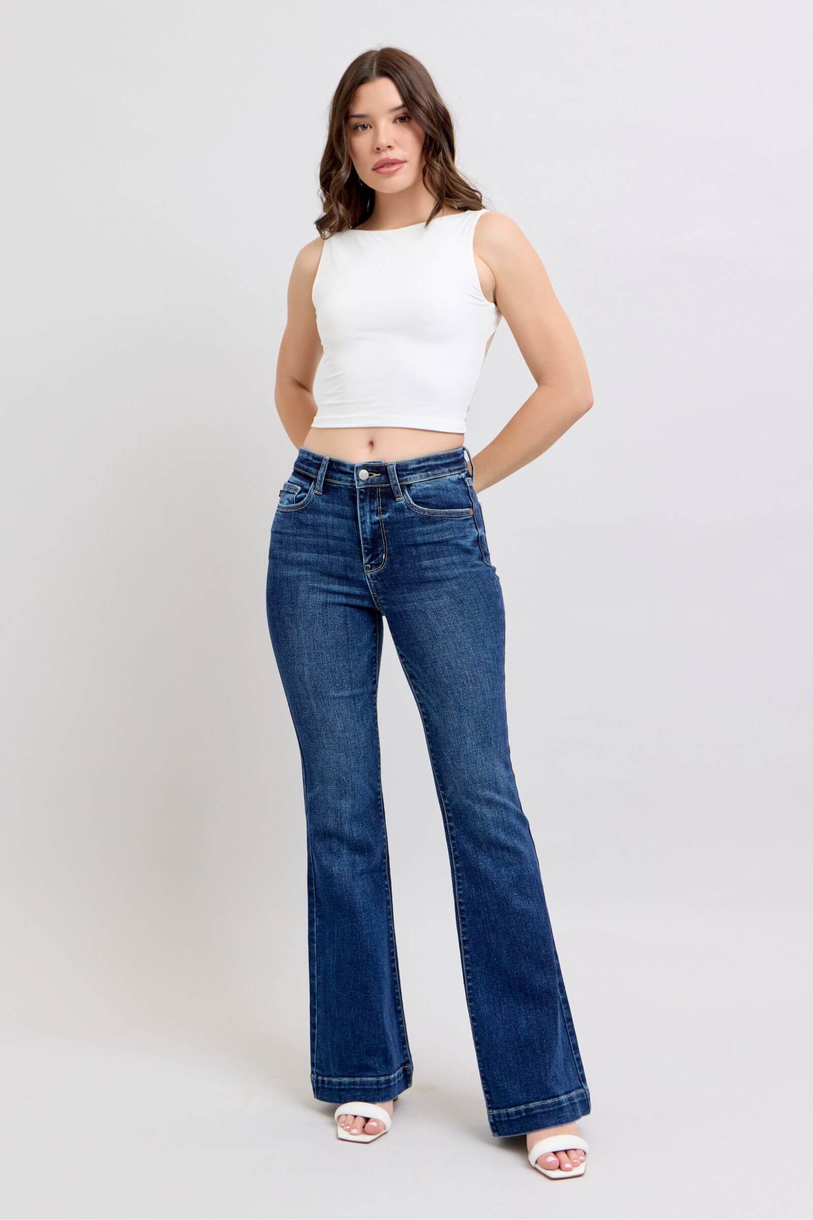 Model wearing Judy Blue high rise flare jeans with pockets, styled with a cropped top and heeled sandals.