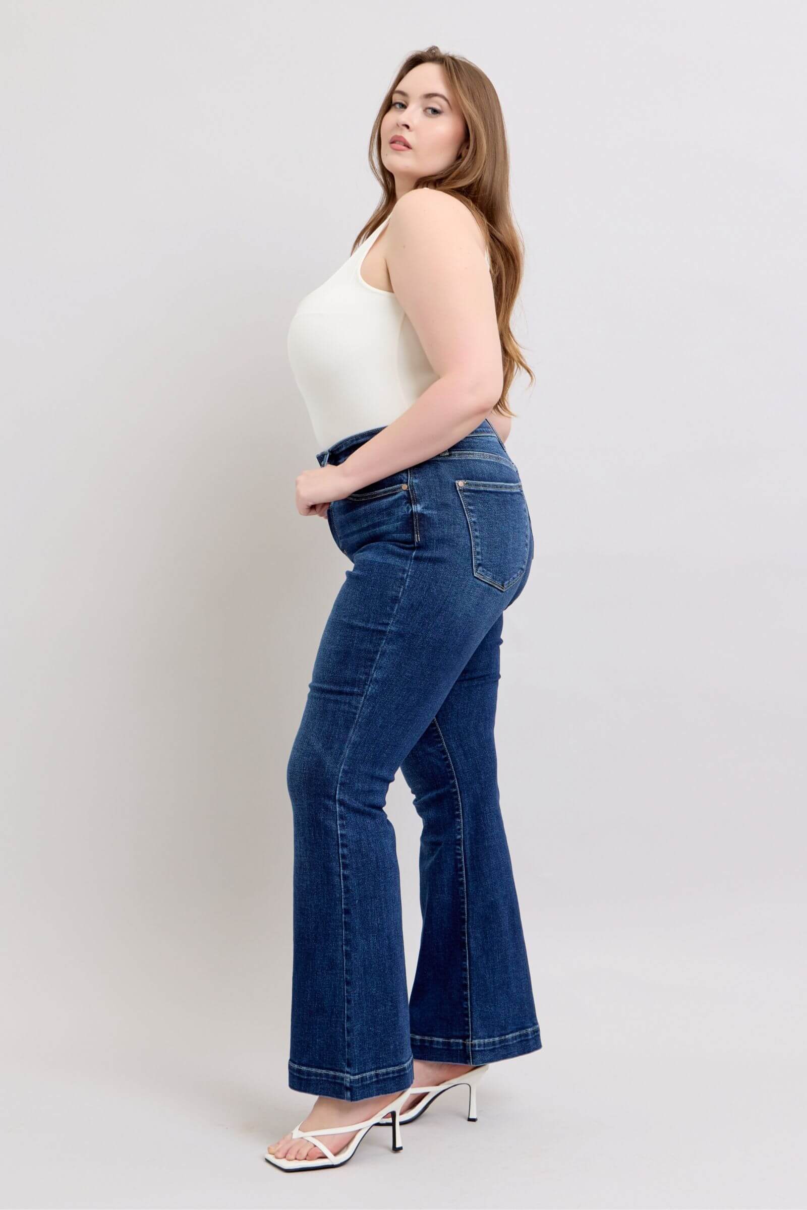 Model showcasing Judy Blue high rise flare jeans with pockets, styled for a chic look.