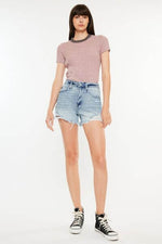 Model showcasing Kancan distressed high waist denim shorts with pockets and a stylish top.