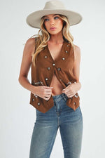 Stylish woman in heart rivet detail suede vest coat and hat, showcasing a chic sleeveless fashion statement.
