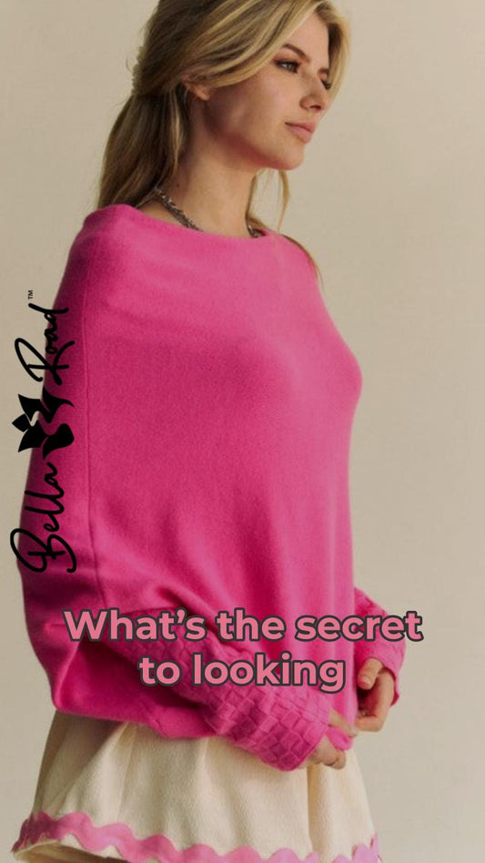 Woman wearing a vibrant pink batwing sleeve sweater, showcasing casual chic style with a playful caption.