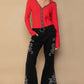 Stylish model wearing red button-up top and black embroidered flare pants, showcasing a trendy bohemian look.