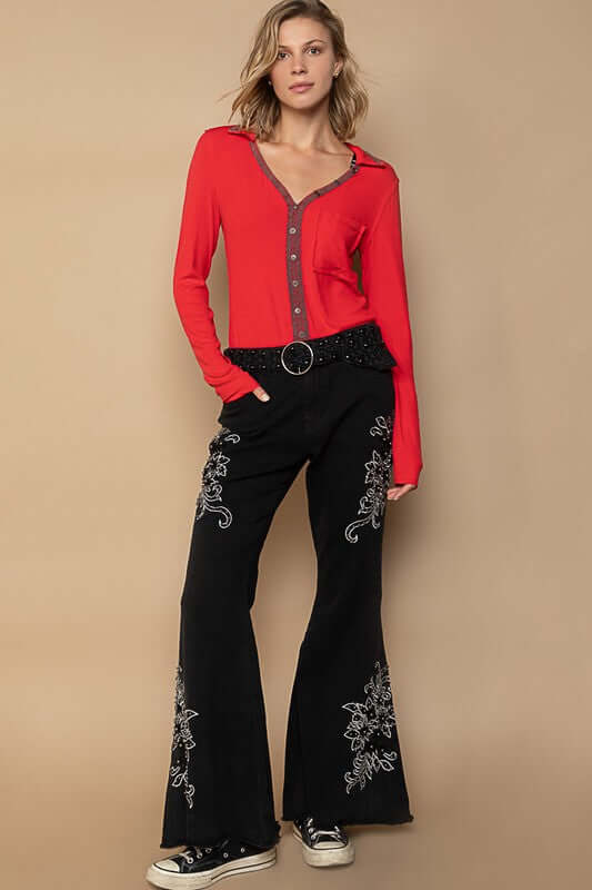 Stylish model wearing red button-up top and black embroidered flare pants, showcasing a trendy bohemian look.