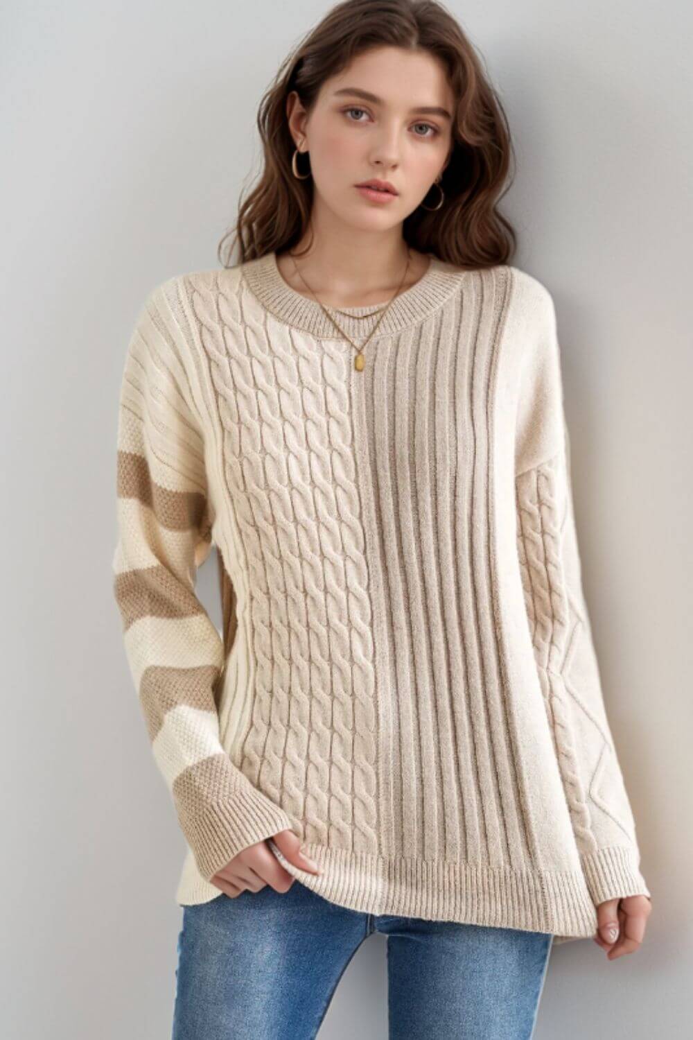 Woman wearing Bella Road cable-knit color block round neck tan sweater, showcasing stylish and cozy fashion.