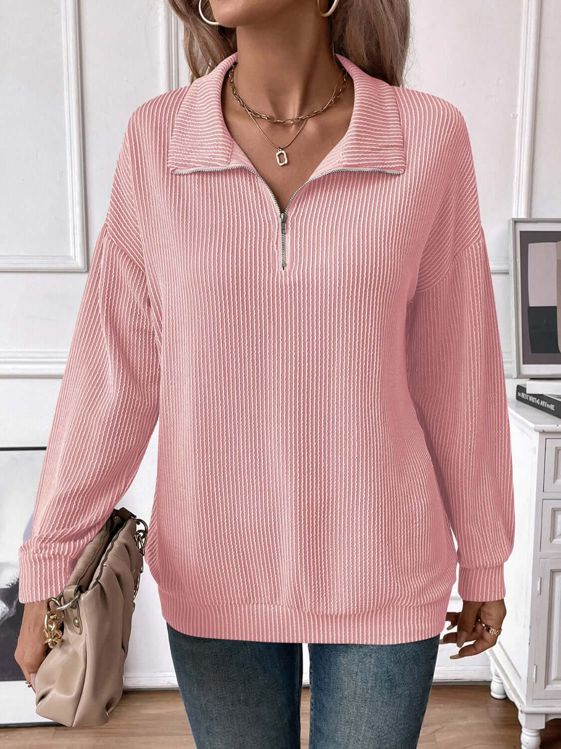 Woman wearing a striped half zip pink long sleeve t-shirt with a slightly stretchy, opaque fabric made of polyester, rayon, and elastane.