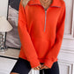 Woman wearing Ivy Lane Half Zip Raglan Sleeve Sweatshirt in vibrant orange color with pocket, styled with black shorts