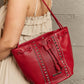 Woman holding Nicole Lee USA Amy Studded Bucket Bag in red vegan leather with stud and zipper detailing