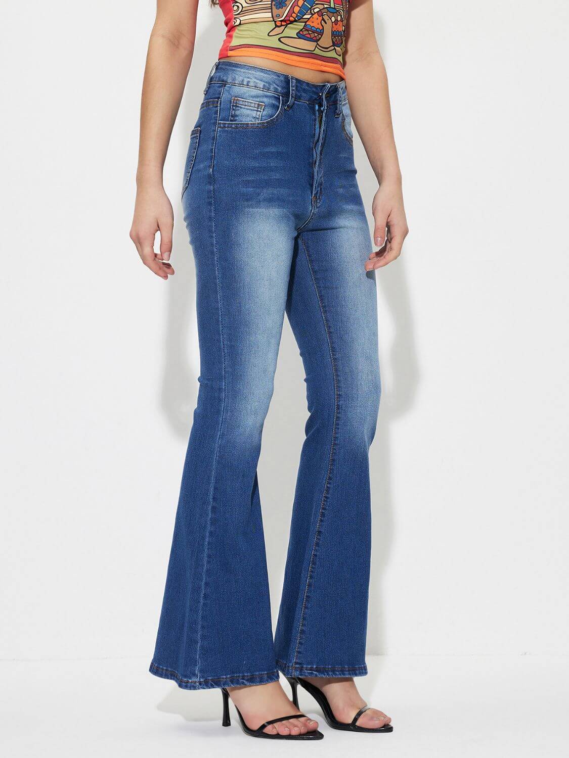 Woman wearing mid-rise waist bootcut jeans with pockets and buttons, no stretch, made of 85% cotton and 15% polyester.