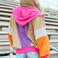 Woman wearing a Drawstring Color Block Zip Up Long Sleeve Hoodie with denim shorts, featuring vibrant pink, purple, beige, and orange sections.