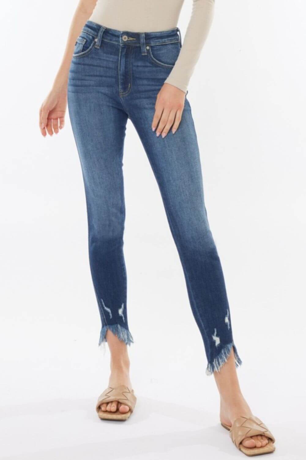 Trendy high waist cropped jeans with raw hem detail modeled with beige top and sandals for a chic, modern look.