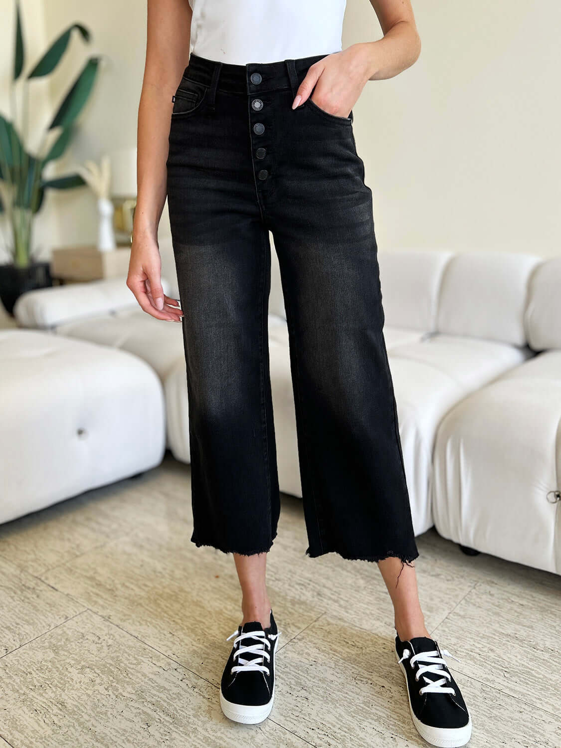 Woman wearing High Waist Button Fly Jeans in black, showcasing stylish and trendy design with button fly closure.