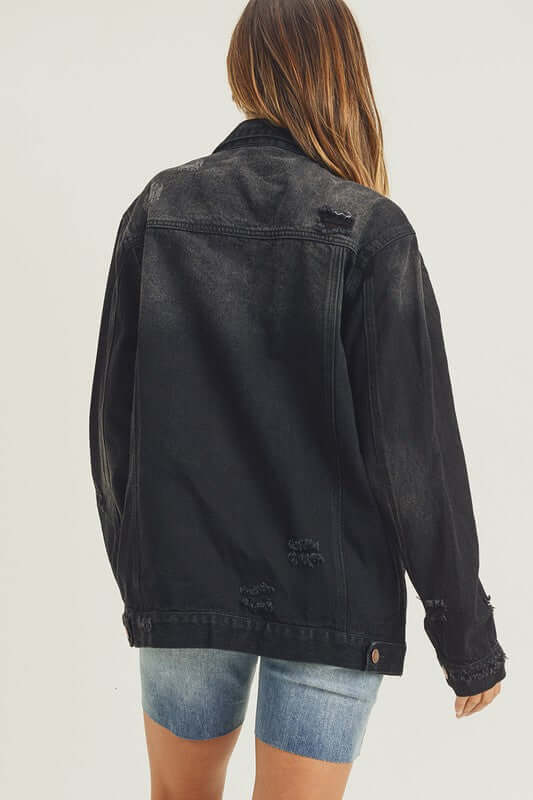 Back view of RISEN distressed long sleeve denim jacket, styled with casual shorts for a trendy look.