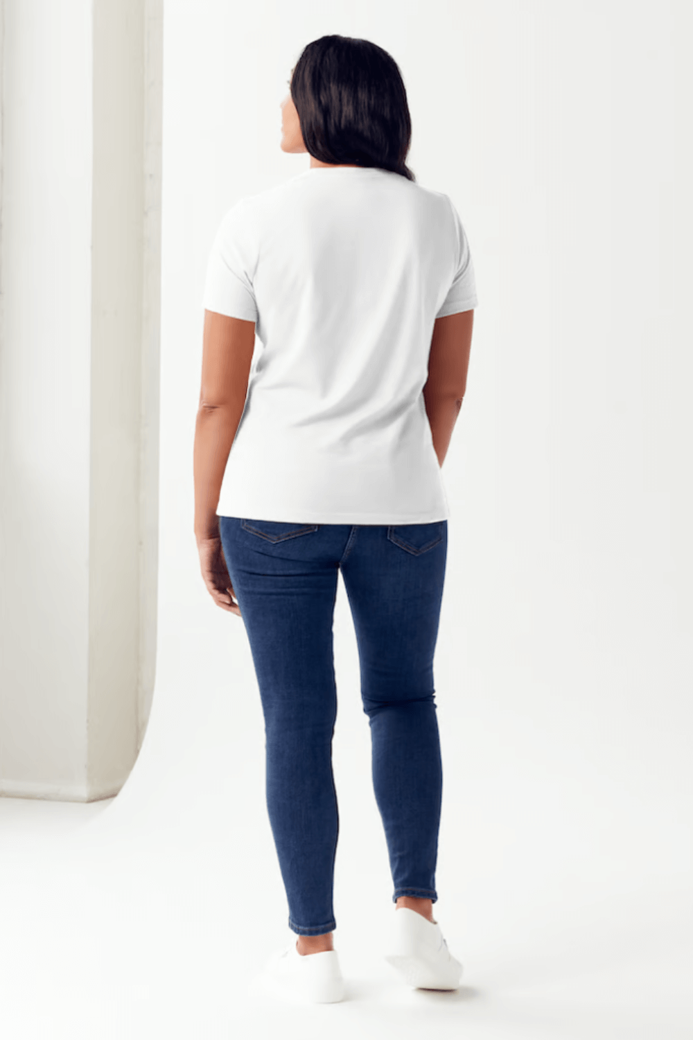 Woman wearing a white Simply Love Graphic Round Neck Short Sleeve Tubular T-Shirt and jeans, viewed from the back.