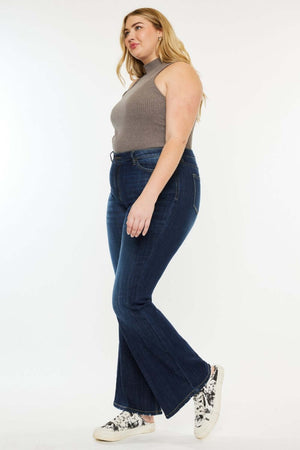 Woman wearing Mid Rise Petite Flare Jeans in dark stone wash with stretch fabric and zip fly closure, paired with a sleeveless top and sneakers.