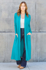 Woman wearing an open front long sleeve cover up in teal, featuring pockets and a slightly stretchy material of rayon and spandex.