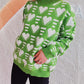 Woman wearing Bella Road Heart Contrast Long Sleeve Dropped Shoulder Sweater in green with heart patterns, showcasing comfort and quirky style.