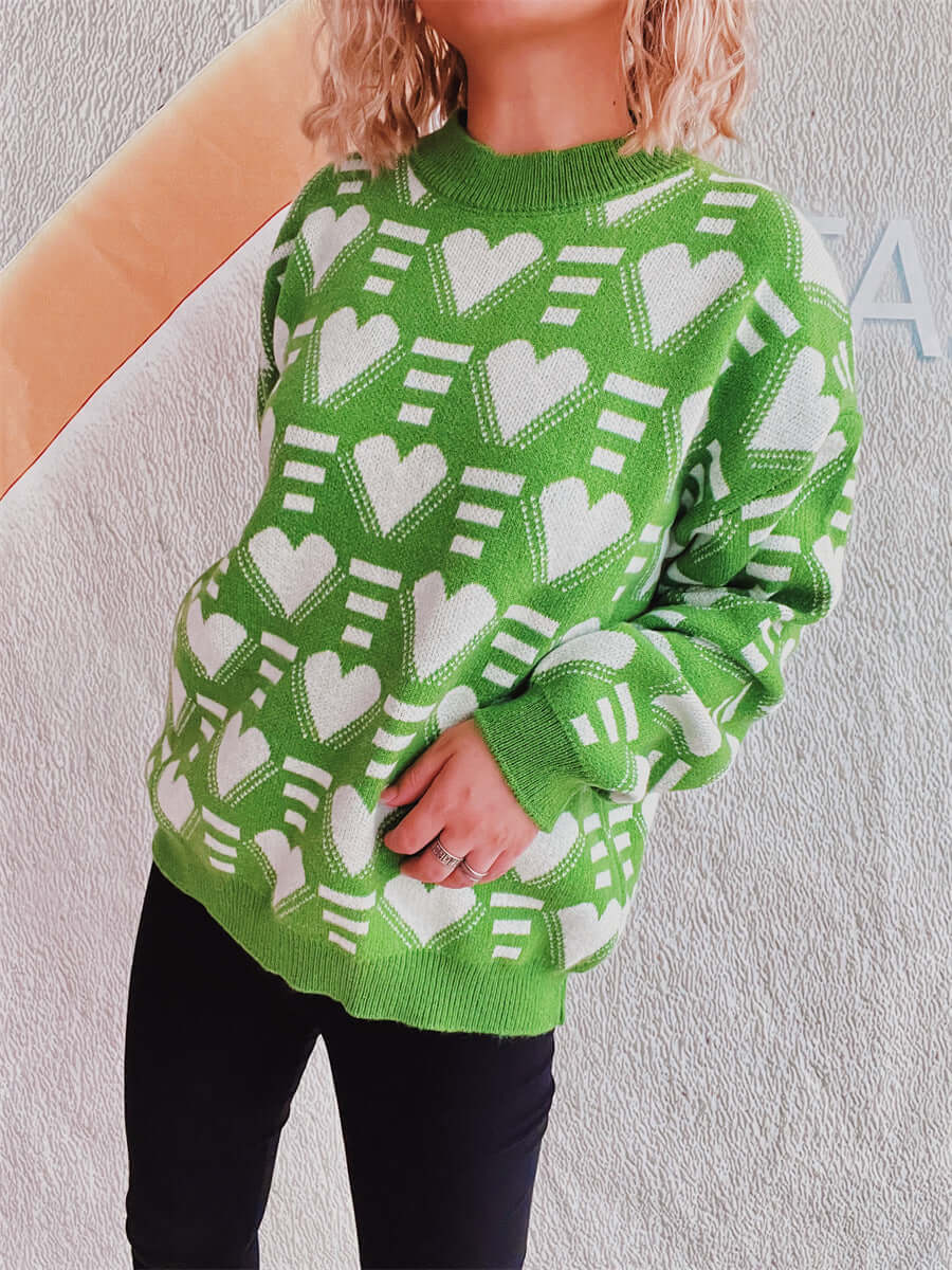 Woman wearing Bella Road Heart Contrast Long Sleeve Dropped Shoulder Sweater in green with heart patterns, showcasing comfort and quirky style.