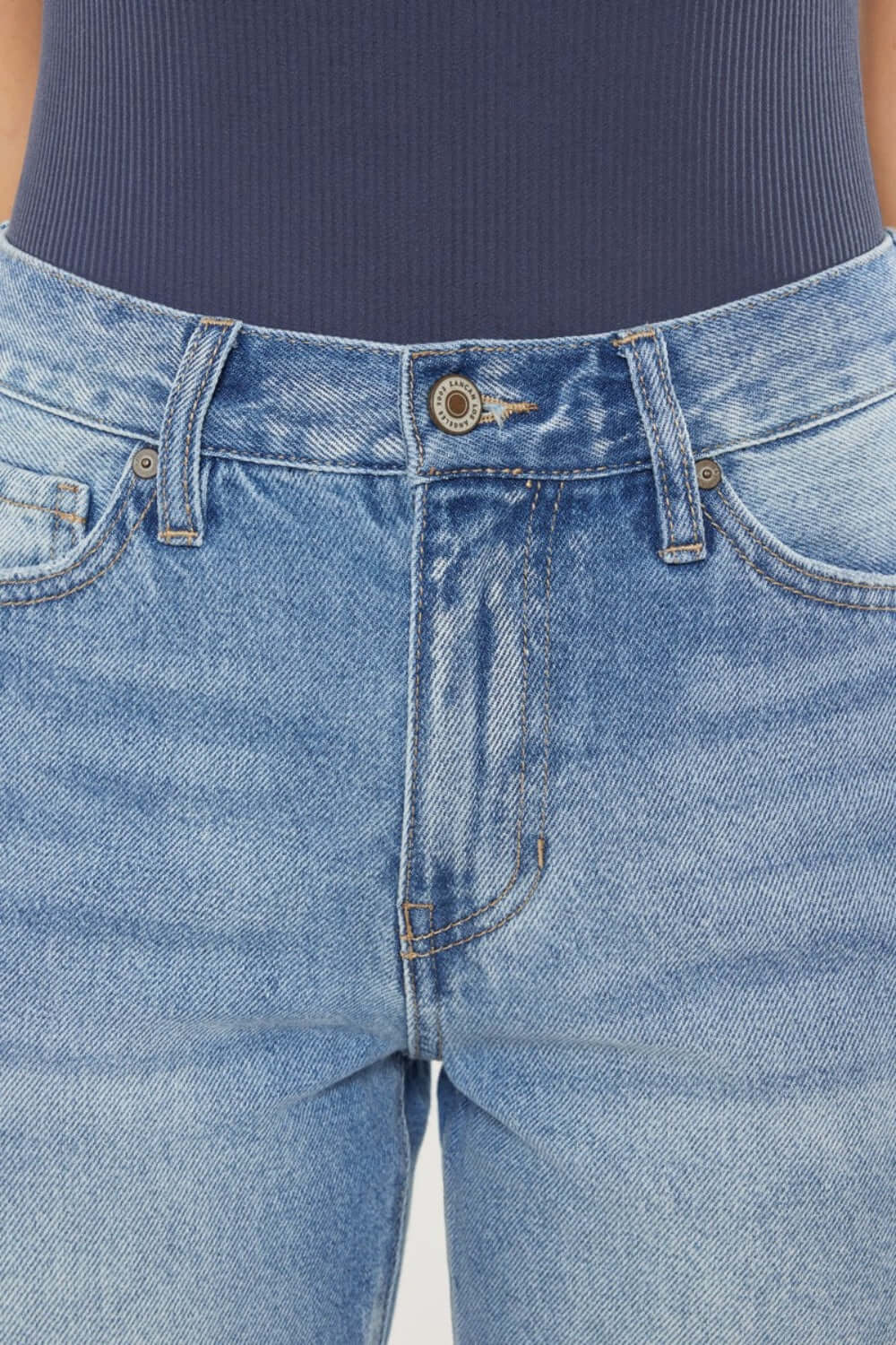 Close-up of high waist chewed up straight mom jeans with distressed detailing and frayed edges.