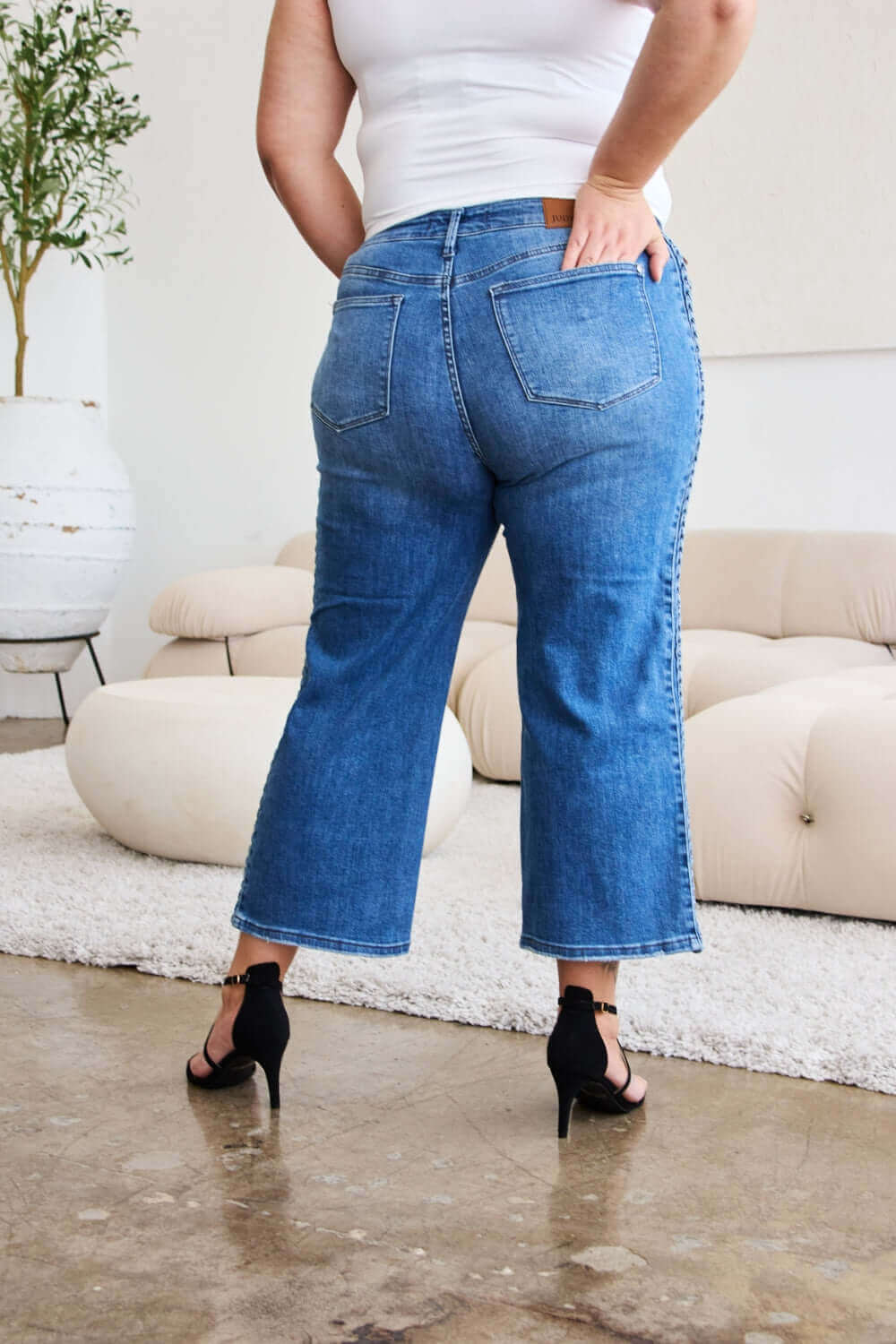 Woman modeling Judy Blue Jeans with braid side detail and wide leg silhouette, back view.