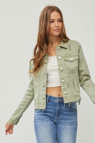 Trendy cropped denim jacket with raw hem, styled with a white top and blue jeans, perfect for a casual chic look.