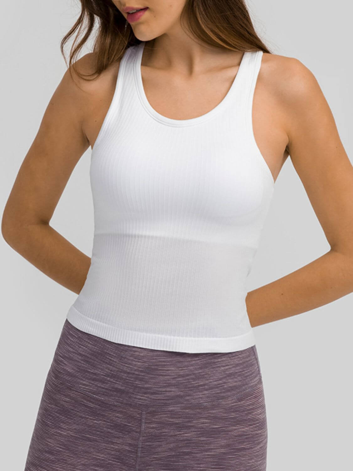 Woman wearing a white round neck racerback active tank top, showcasing comfort and style for workouts.