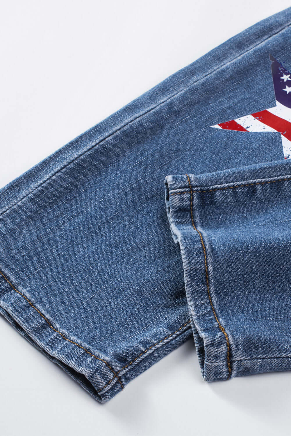 Close-up of Bella Road distressed straight jeans with pockets, featuring flag detail. 75% cotton, 24% polyester, 1% elastane. Slightly stretchy fabric.