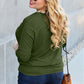 Plus-size model wearing round neck batwing sleeve top in green, paired with blue jeans and brown handbag