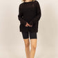 Model wearing HYFVE Distressed Long Sleeve Knit Top with relaxed fit, paired with black shorts and comfy slippers.