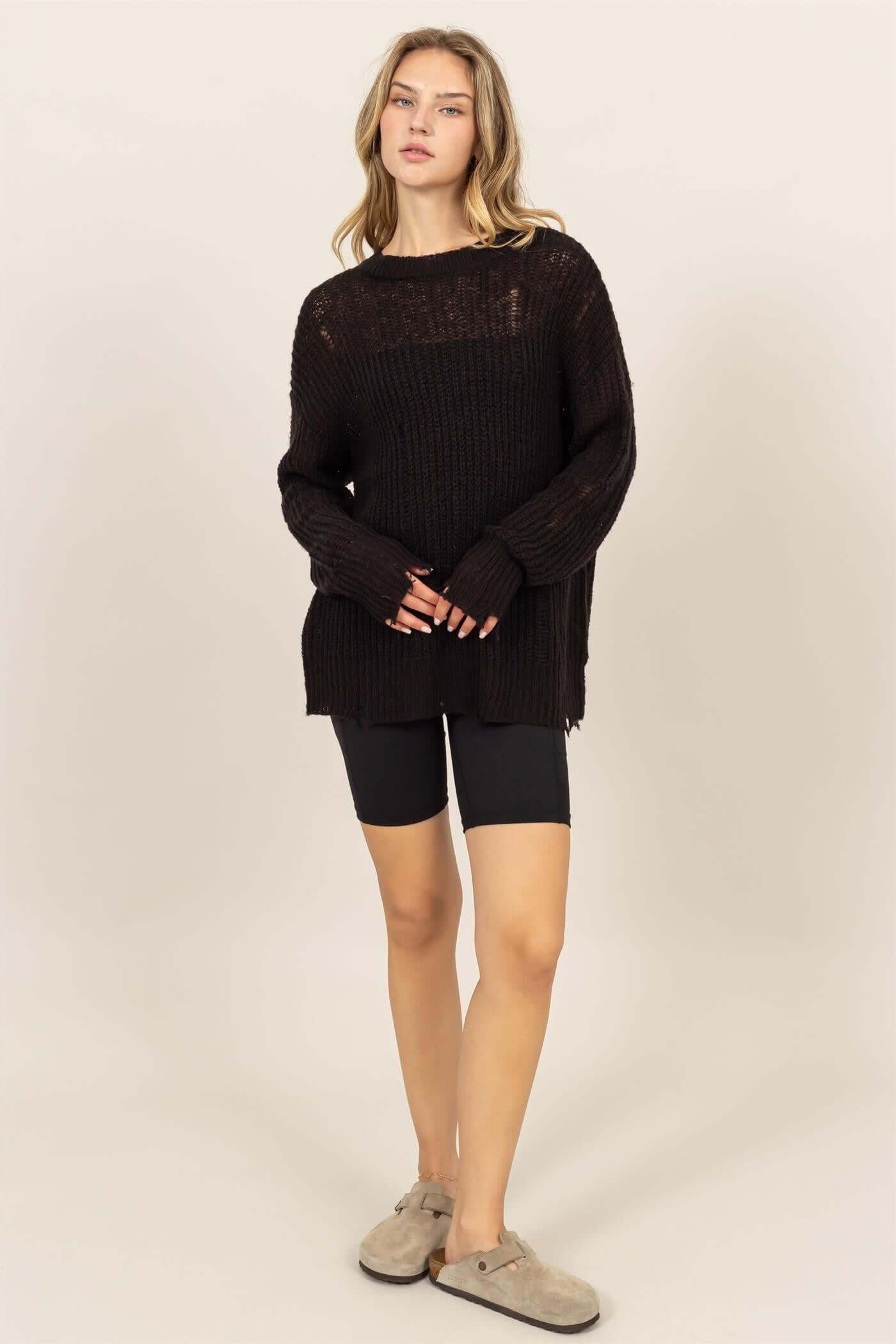 Model wearing HYFVE Distressed Long Sleeve Knit Top with relaxed fit, paired with black shorts and comfy slippers.