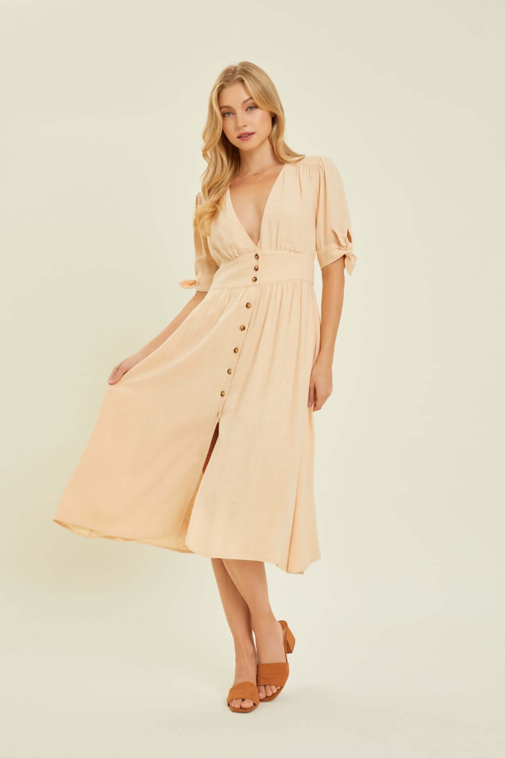 Woman wearing HEYSON full size textured linen V-neck button-down midi dress in warm weather setting.