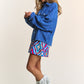 Woman wearing J.NNA Snap Down Long Sleeve Denim Shacket with colorful skirt and fringe boots, smiling side profile.