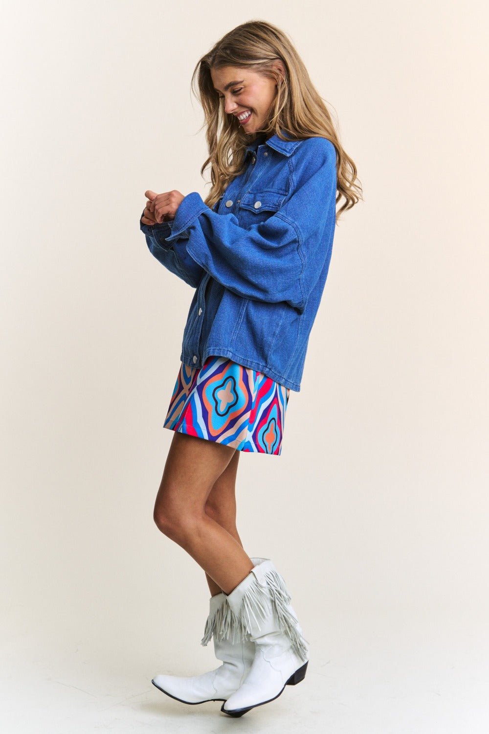 Woman wearing J.NNA Snap Down Long Sleeve Denim Shacket with colorful skirt and fringe boots, smiling side profile.