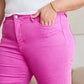 Woman wearing pink RFM Jeans with high waist and tummy control features, showing stylish raw hem and gold bracelet.