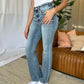 Woman wearing Judy Blue medium rise bootcut jeans in a stylish living room setting.