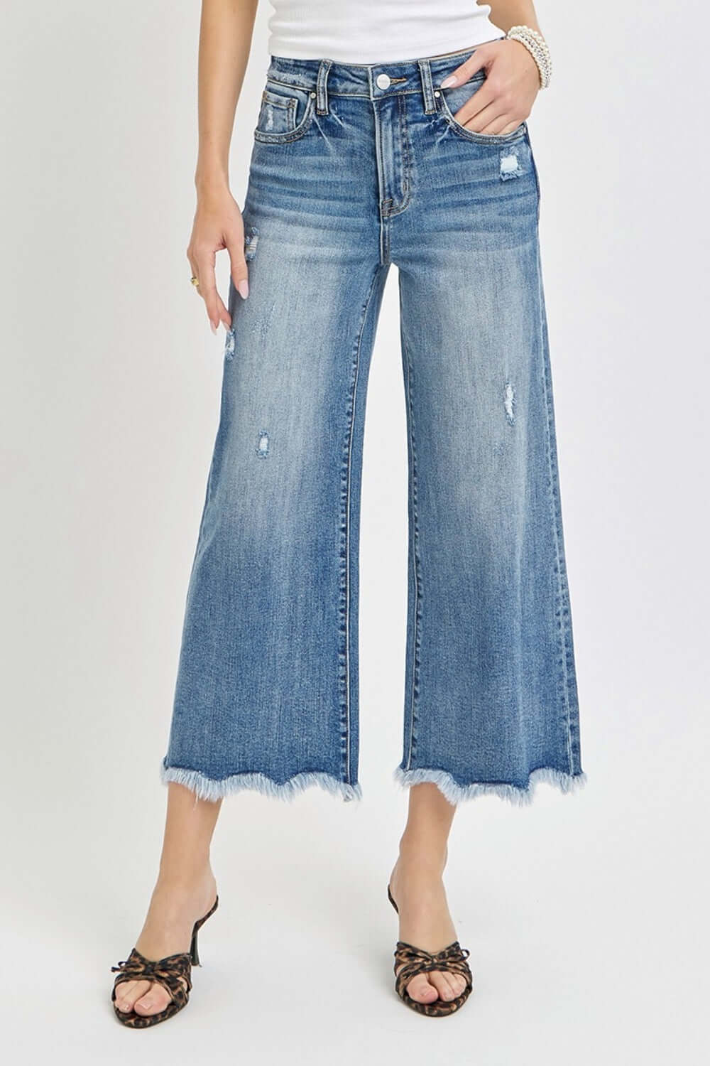 Woman wearing Risen Jeans high rise cropped flare jeans with a modern chic style, showcasing distressed details and frayed hems