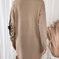 Back view of Perfee Flower Mock Neck Long Sleeve Sweater Dress in tan with flower detail on sleeve, wooden floor and white curtains in the background