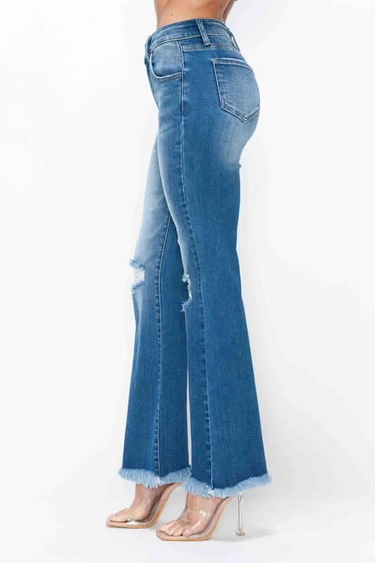 Side view of bytos full size raw hem distressed high rise bootcut jeans showcasing trendy flared design and unique detailing.