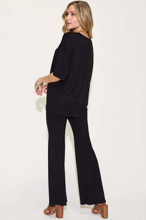 Woman wearing a black Bamboo Drop Shoulder T-Shirt and Flare Pants Set, standing and looking back.