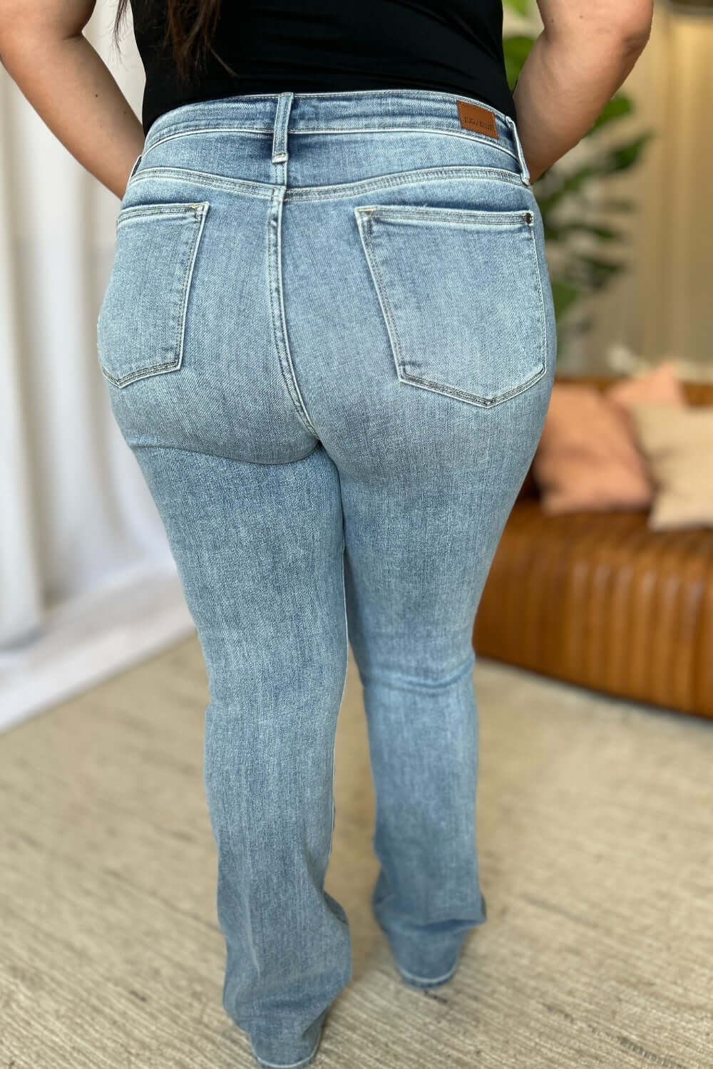 Woman wearing Judy Blue full size medium rise bootcut jeans, showcasing the flattering fit and slight flare design for a balanced silhouette.