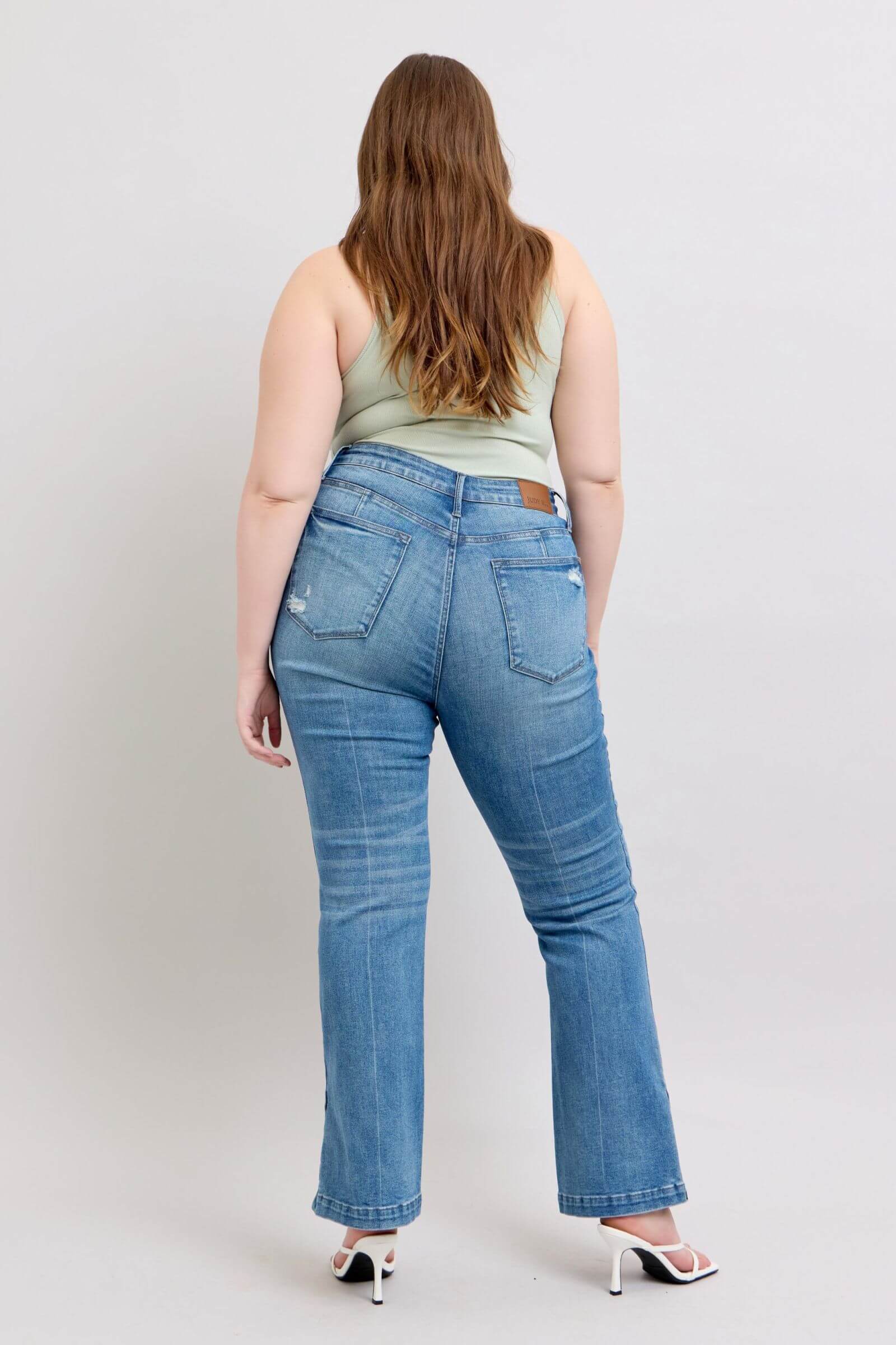 Back view of a model wearing Judy Blue high waist bootcut jeans, showcasing their vintage wash and flattering fit.