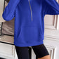 Woman wearing Ivy Lane Half Zip Raglan Sleeve Sweatshirt in blue with zippered front and pocket, perfect for casual wear.